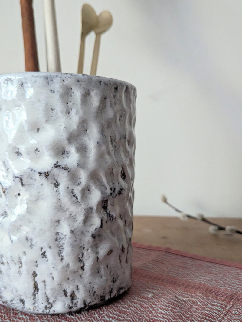 Textured ceramic vase with sticks on a neutral background