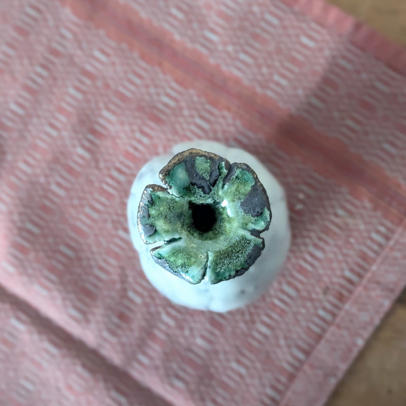 Close-up of the top of the vase which is a green flower design on a textured pink surface