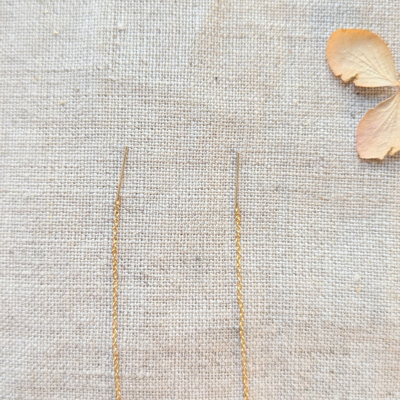 Delicate gold thread earring end on linen cloth