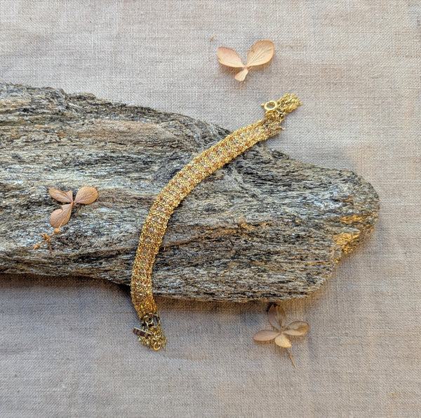 Gold bracelet on a textured surface with leaves