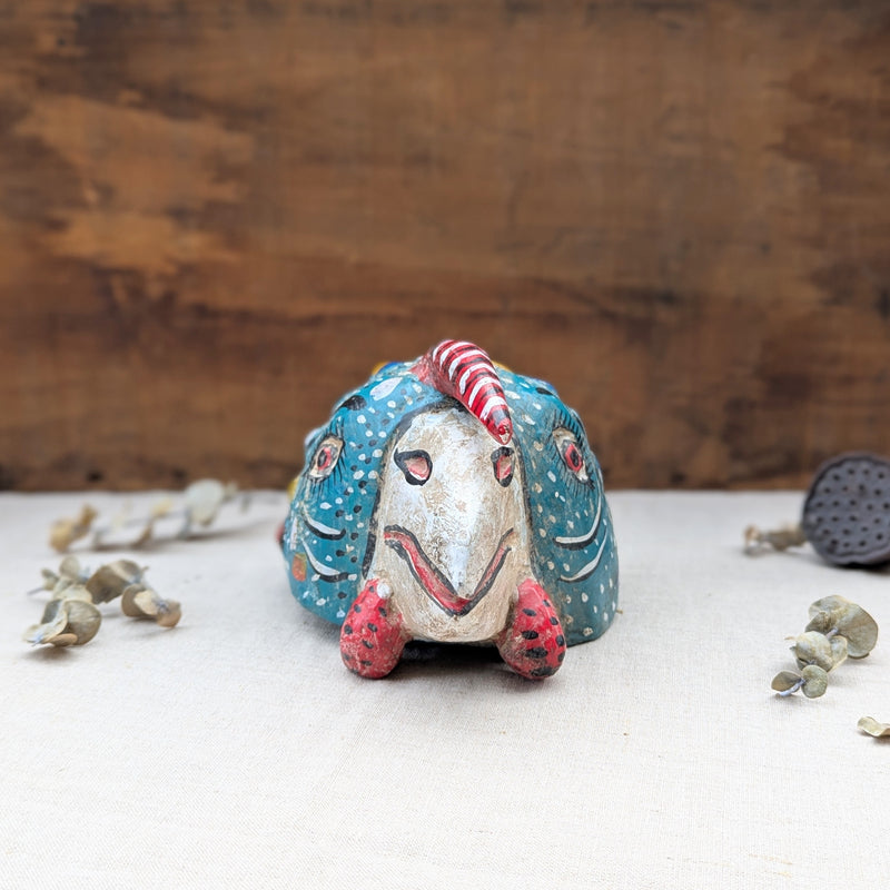 front view of a blue wooden rooster mask on a neutral background.