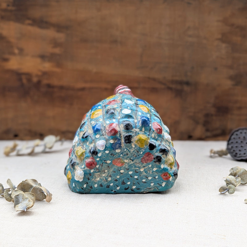 Bcak view of a blue wooden rooster mask on a neutral background.