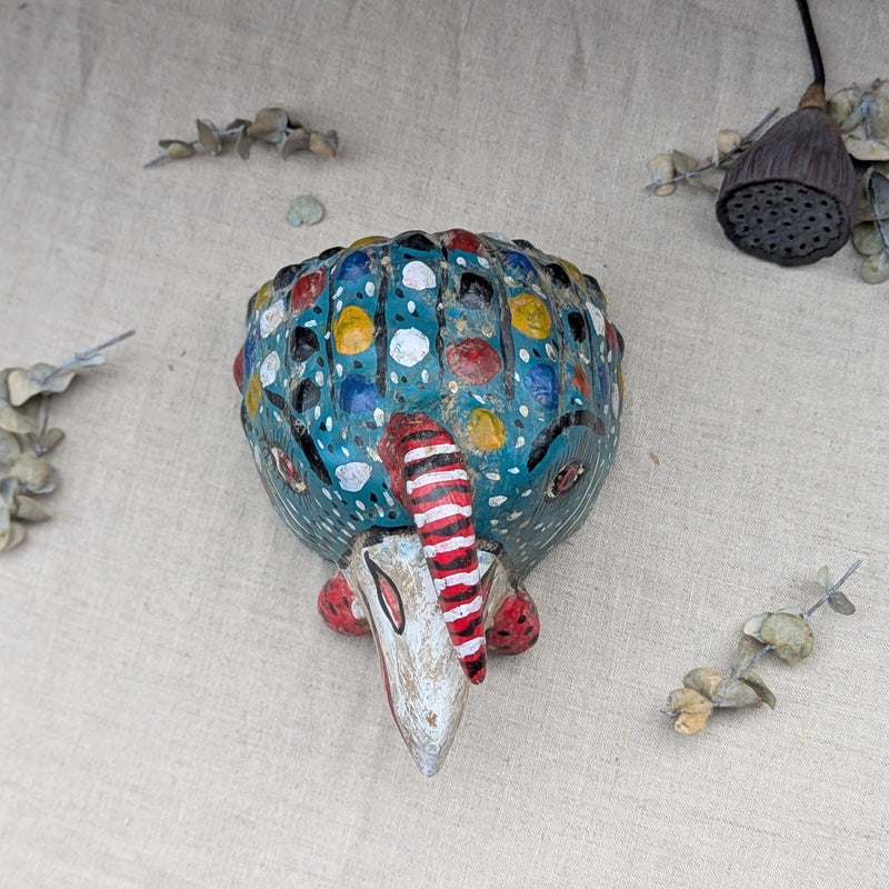 top view of a blue wooden rooster mask on a neutral background.