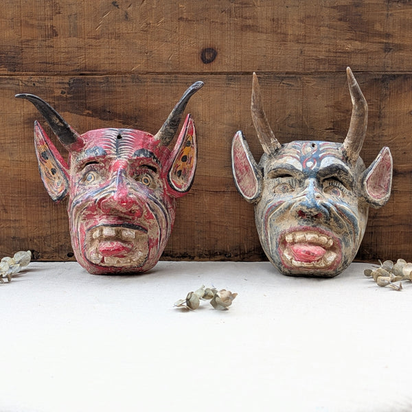 Red and blue wooden devil masks on neutral back ground