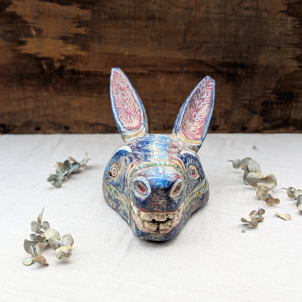front view of blue wooden donkey mask on neutral background