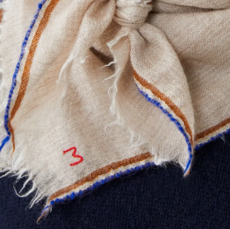 Close-up of a beige fabric with brown and blue stitching on a dark background