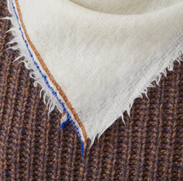 Close-up of a beige scarf eith brown and blue stripped trimming.