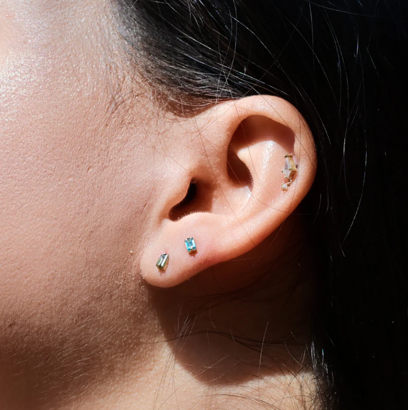 Close-up of an ear with multiple earrings on a dark background