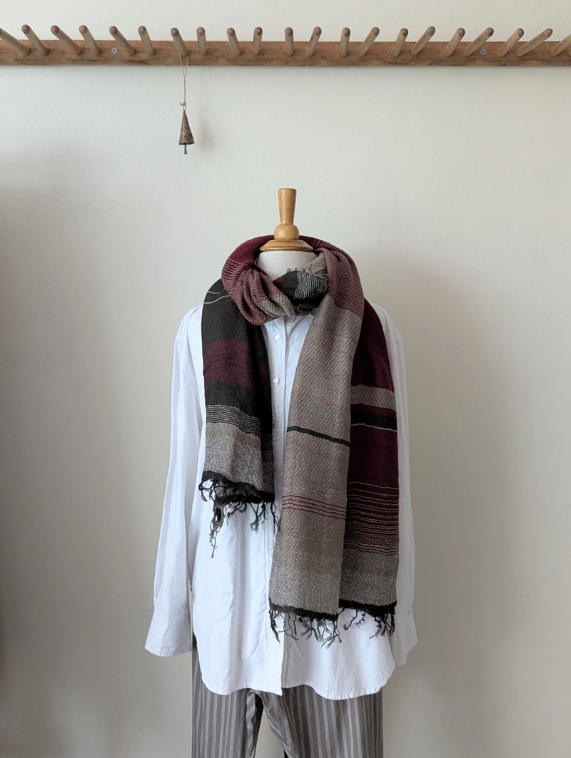Mannequin wearing a white shirt and striped scarf against a plain wall.