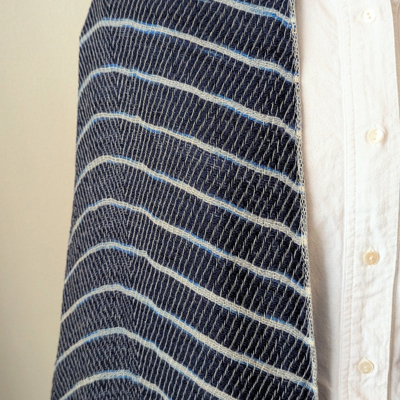 Close-up of a blue and white striped fabric with a white shirt in the background