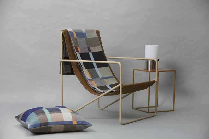 Modern chair with plaid cushion and matching pillow on a gray background