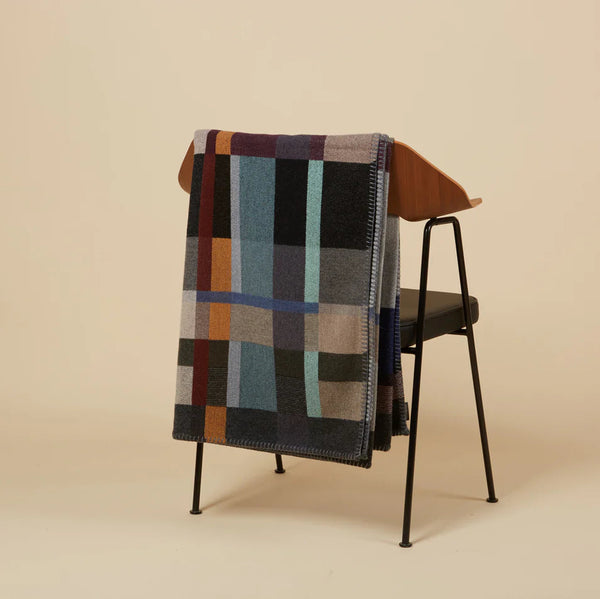 Multicolored checkered blanket draped over a chair on a beige background