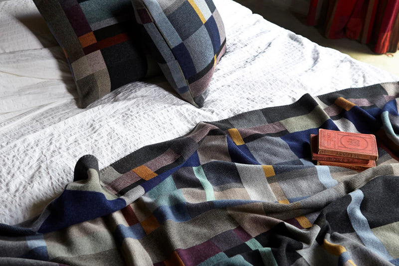 Plaid blanket draped over a bed with pillows in the background