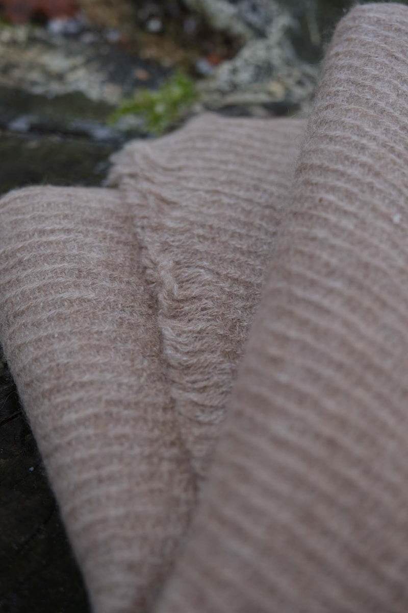 Close-up of textured cashmere scarf with a blurred natural background
