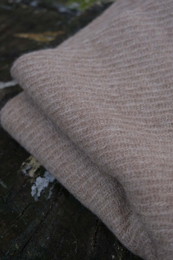 Close-up of a folded beige scarf on a dark surface