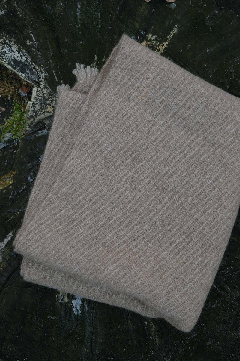 Folded beige scarf on a textured dark surface