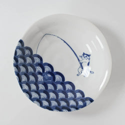 White ceramic dish with blue wave and a cat fisherman design on a white background