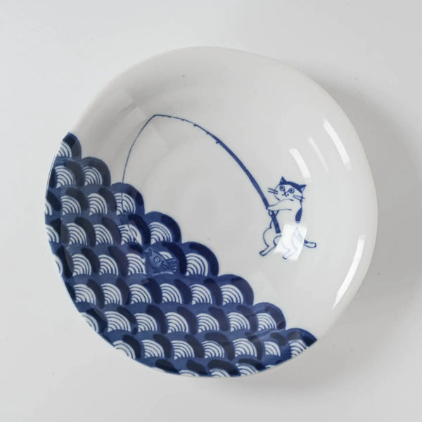 White ceramic dish with blue wave and a cat fisherman design on a white background