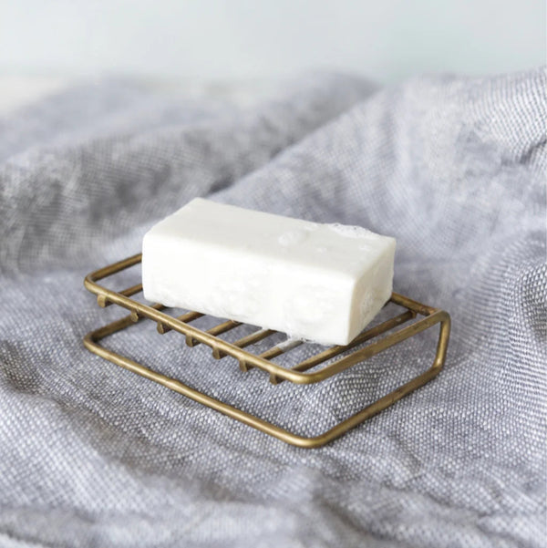 Bar of soap on a brass soap stand with a soft gray fabric background.

Fog Linen brass bar soap stand bath shower home decor kitchen Boston gift shop store boutique
