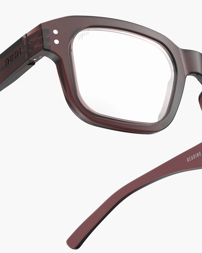 Close-up of a pair of glasses with a maroon frame on a white background