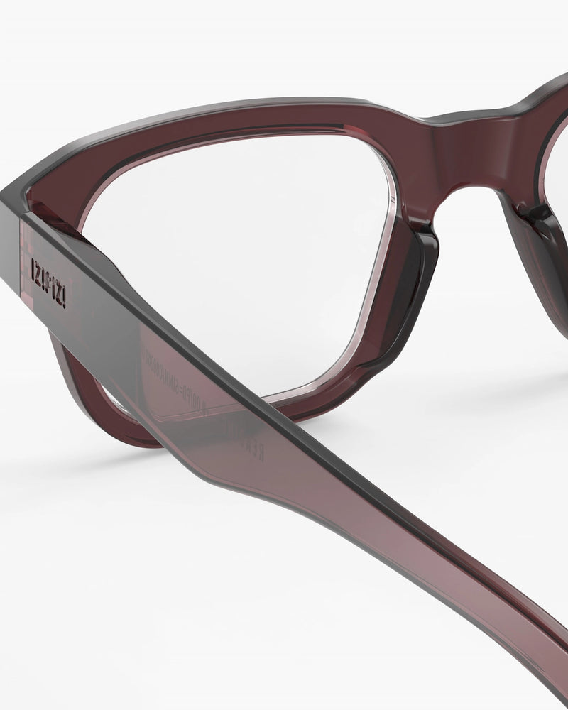 Close-up of a pair of glasses with a maroon frame on a white background