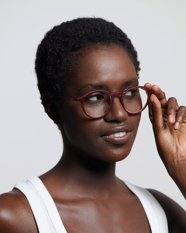 Woman wearing red glasses against a plain background