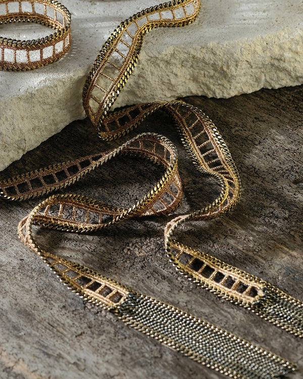 Decorative ribbon  necklace with metallic pattern on a textured surface