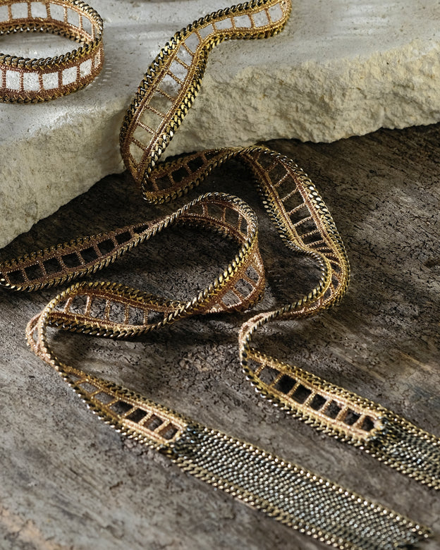 Decorative ribbon  necklace with metallic pattern on a textured surface