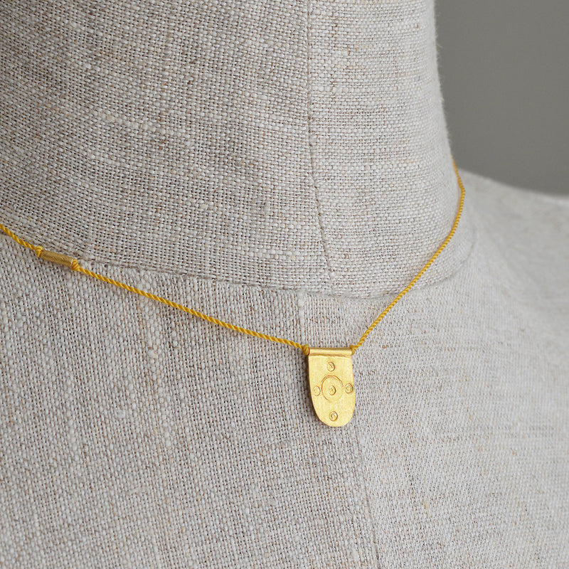 Tab talisman necklace by River Song jewelry. 24k gold over sterling silver. Nylon cord.