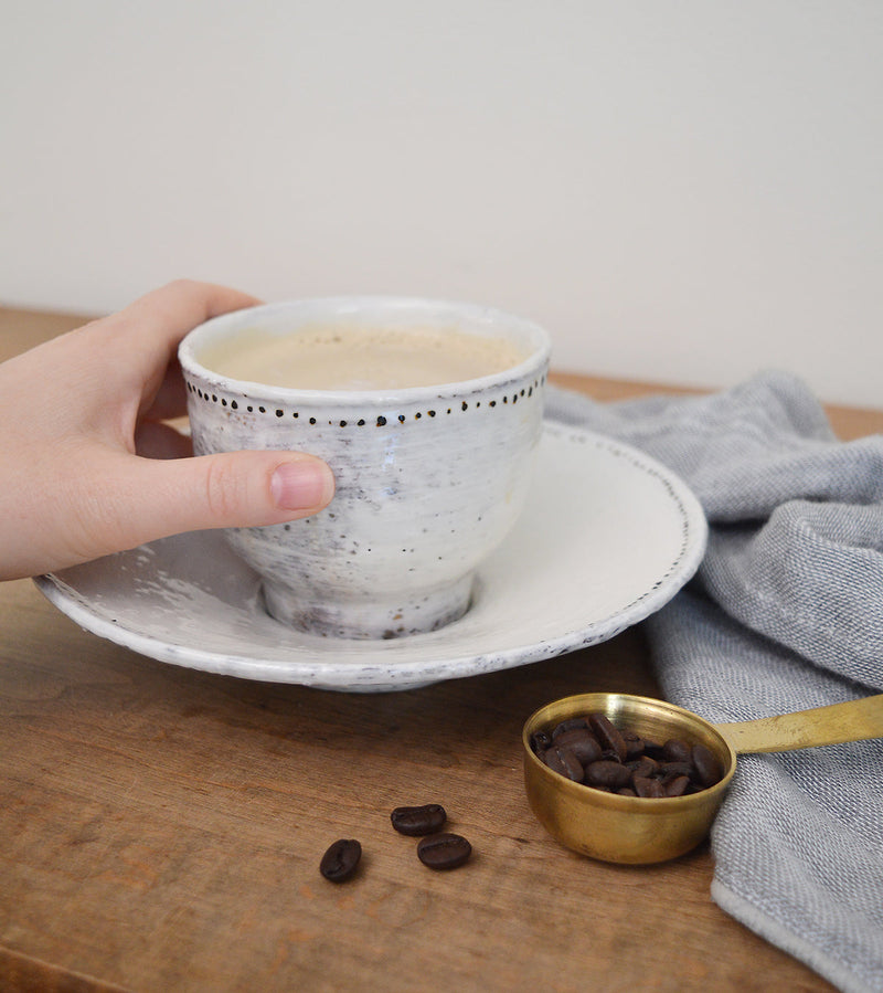 Adorable bowl and matching saucer by French artist Florence Penault. Sized perfectly for ice cream, a cup of soup, or a dip! Tiny hand painted black dots adorn the edges adding a touch of sophistication to the organic look of the glaze.