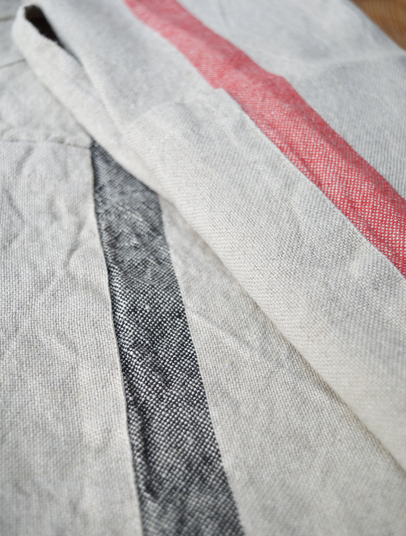 Half apron made of heavy weigh linen. An offset stripe and a large pocket divided in two make this utilitarian apron a durable and stylish kitchen companion.  