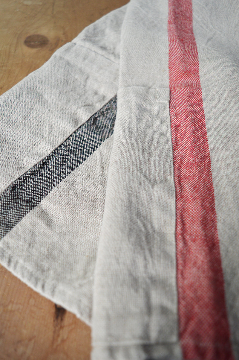 Half apron made of heavy weigh linen. An offset stripe and a large pocket divided in two make this utilitarian apron a durable and stylish kitchen companion.  